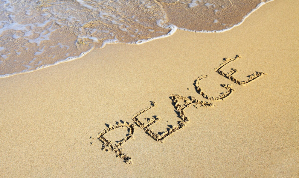 the word Peace written in the sand