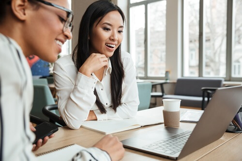 two women coworkers looking at a laptop